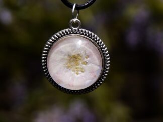Nahaufnahme eines handgefertigten Cabochon-Anhängers mit echter Kirschblüte hinter klarem Glascabochon (20 mm), eingefasst in eine silberfarbene Metallfassung mit Perlrand.