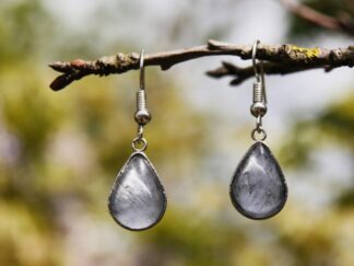 Zarte Ohrringe mit Edelstahlhaken und tropfenförmigem Glascabochon, hinter dem eine blau-graue Hortensienblüte eingefasst ist – natürlicher Schmuck in eleganter Tropfenform.