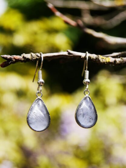 Zarte Ohrringe mit Edelstahlhaken und tropfenförmigem Glascabochon, hinter dem eine blau-graue Hortensienblüte eingefasst ist – natürlicher Schmuck in eleganter Tropfenform.