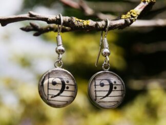 Edelstahl-Ohrringe mit Haken und 12 mm Glascabochons, hinter denen ein Bassschlüssel auf antikem Notenpapier eingefasst ist – handgefertigter musikalischer Schmuck.