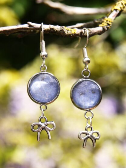 Ohrringe mit Edelstahlhaken, 12 mm Glascabochons mit eingefasster blau-grauer Hortensienblüte und dekorativem Schleifencharm – handgefertigter Naturschmuck.