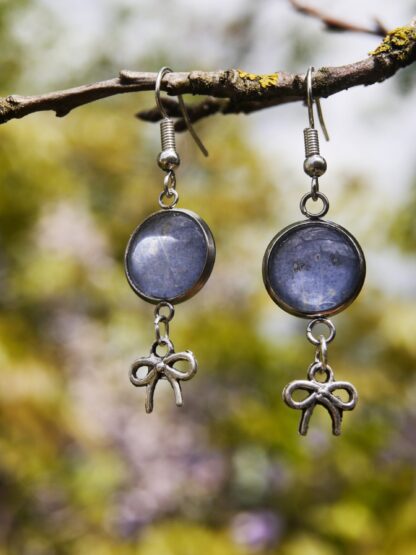 Ohrringe mit Edelstahlhaken, 12 mm Glascabochons mit eingefasster blau-grauer Hortensienblüte und dekorativem Schleifencharm – handgefertigter Naturschmuck.