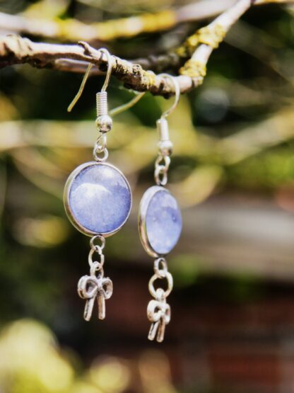 Ohrringe mit Edelstahlhaken, 12 mm Glascabochons mit eingefasster blau-grauer Hortensienblüte und dekorativem Schleifencharm – handgefertigter Naturschmuck.